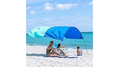 The image shows a stylish beach cabana providing shade and wind protection on a sandy shore.