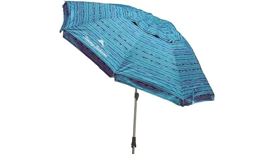 The image shows colorful beach umbrellas providing shade on a sunny day, some tilted against the wind.