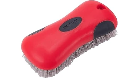 The image shows a patio cushion being cleaned with a spray bottle and brush, perhaps one of the best cleaners.