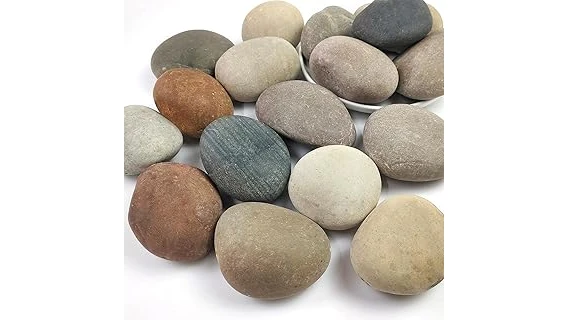 The image shows colorful, decorative rocks arranged attractively around flowering plants in a garden bed.
